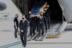 The coffin of one of the six humanitarian aid workers from the French NGO ACTED killed by gunmen in a Niger, is carried out of a military transport plan during a ceremony at Orly Airport, south of Paris, Aug. 14, 2020.