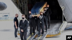 The coffin of one of the six humanitarian aid workers from the French NGO ACTED killed by gunmen in a Niger, is carried out of a military transport plan during a ceremony at Orly Airport, south of Paris, Aug. 14, 2020.