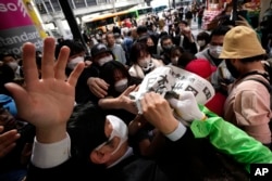 An employee distributes extra editions of the Yomiuri Shimbun newspaper reporting on Japan's victory at the final match of the World Baseball Classic Wednesday, March 22, 2023, in Tokyo. The headline of the newspaper said "Japan is No. 1 in the World." (AP Photo/Eugene Hoshiko)