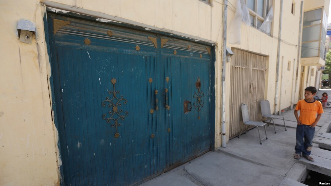 FILE - An Afghan boy looks at the entrance gate of a house, where a German aid worker and an Afghan guard were killed the night before, in Kabul, May 21, 2017. 