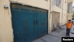 FILE - An Afghan boy looks at the entrance gate of a house, where a German aid worker and an Afghan guard were killed the night before, in Kabul, May 21, 2017. 