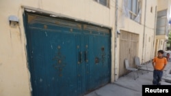 An Afghan boy looks at the entrance gate of a house, where a German aid worker and an Afghan guard were killed last night, in Kabul, May 21, 2017. 