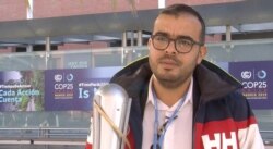 Moroccan activist Ayoub Makhloufi holding an eco-friendly torch, transported between each climate conference, like the Olympic one. Lisa Bryant. (L. Bryant/VOA)