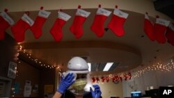 FILE - Nurse Romina Pacheco disinfects her respirator after tending to a patient in a COVID-19 unit decorated with Christmas stockings with nurses' names on them at Mission Hospital in Mission Viejo, Calif., Dec. 21, 2020.