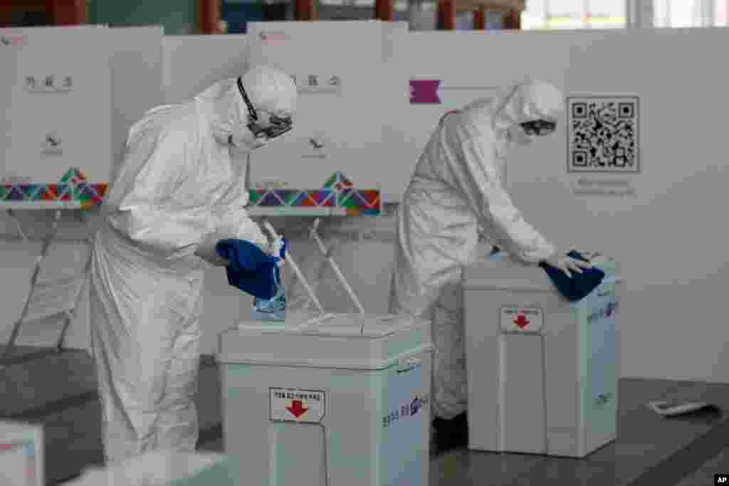Workers wearing protective gear disinfect ballot boxes ahead of early voting for the upcoming Seoul mayoral by-election at a local polling station in Seoul, South Korea.