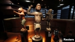 FILE - Three large royal statues of the Kingdom of Dahomey are displayed at the Quai Branly Museum in Paris, France, Nov. 23, 2018. 