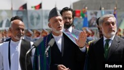 FILE - Afghan President Hamid Karzai (C) speaks during celebrations to commemorate Afghanistan's 95th anniversary of independence as he is flanked by presidential candidates Abdullah Abdullah (R) and Ashraf Ghani in Kabul, August 19, 2014. 