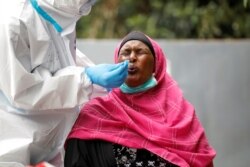A woman reacts as a health worker takes a swab during coronavirus testing in the Kawangware neighborhood of Nairobi, Kenya, May 2, 2020.