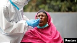 A woman reacts as a health worker takes a swab during coronavirus testing, in the Kawangware neighborhood of Nairobi, Kenya, May 2, 2020.