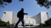 FILE - A man walks past the headquarters of the People's Bank of China, the central bank, in Beijing, China, Sept. 28, 2018. 