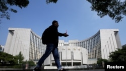 FILE - A man walks past the headquarters of the People's Bank of China, the central bank, in Beijing, China, Sept. 28, 2018. 