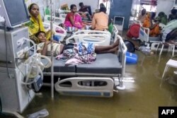 Patients and their relatives rest in beds as they wade through floodwaters during heavy monsoon rain at waterlogged Nalanda Medical College and Hospital in Patna in the northeastern state of Bihar, India, Sept. 28, 2019.