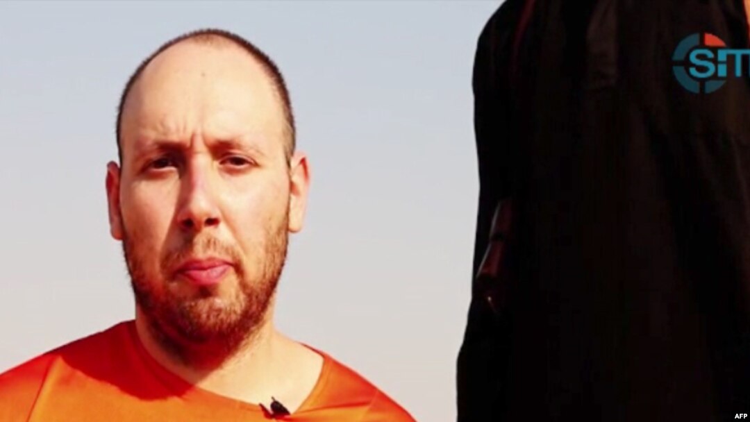An image grab taken from a video released by the Islamic State (IS) and identified by private terrorism monitor SITE Intelligence Group purportedly shows U.S. freelance writer Steven Sotloff dressed in orange and on his knees in a desert landscape speaking to the camera before being beheaded by a masked militant (R), Sept. 2, 2014. 