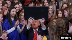 U.S. President Donald Trump holds up the "Keeping Men Out of Women's Sports" executive order after signing it in the East Room of the White House in Washington, Feb. 5, 2025.