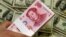 A pack of bills of Chinese yuan next to the U.S. currency