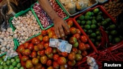 Seorang penjual sayuran menerima uang dari pembeli di sebuah pasar tradisional di Jakarta, 2 Mei 2019. (Foto: Reuters)