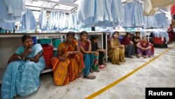 FILE - Employees sit during their lunch time inside a textile mill in India.