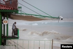 A man looks at the waves of the sea before the arrival of tropical storm Ileana, in Cabo San Lucas, Baja California Sur state, Mexico, Sept. 13, 2024.