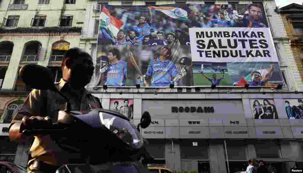 A policeman on a scooter backs out from a parking lot in front of a billboard of cricketer Sachin Tendulkar in Mumbai, Nov. 15, 2013.&nbsp;