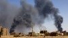 FILE PHOTO: Man walks while smoke rises above buildings after aerial bombardment in Khartoum North