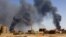 FILE PHOTO: Man walks while smoke rises above buildings after aerial bombardment in Khartoum North. REUTERS/Mohamed Nureldin Abdallah/File Photo