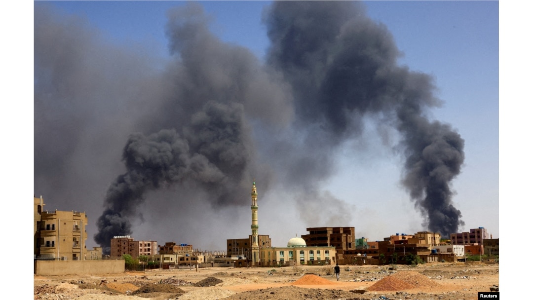 Seorang pria berjalan saat asap mengepul di atas bangunan setelah pengeboman udara di Khartoum Utara. (Foto: Reuters)