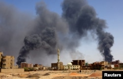 Seorang pria berjalan saat asap mengepul di atas bangunan setelah pengeboman udara di Khartoum Utara. (Foto: Reuters)