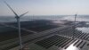 FILE - Wind turbines dot the coastline along a giant solar farm near Weifang in eastern China's Shandong province on March 22, 2024.