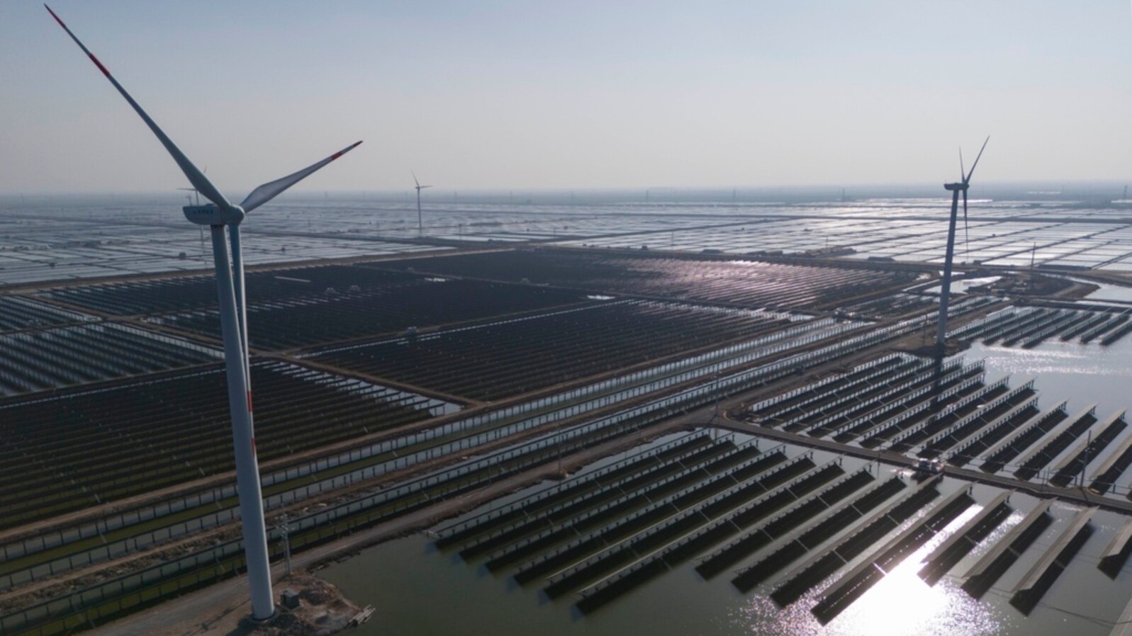 FILE - Wind turbines dot the coastline along a giant solar farm near Weifang in eastern China's Shandong province on March 22, 2024.