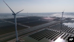 FILE - Wind turbines dot the coastline along a giant solar farm near Weifang in eastern China's Shandong province on March 22, 2024.