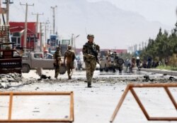 FILE - Afghan security forces and a British soldier with NATO-led Resolute Support Mission stand guard at the site of a suicide attack in Kabul, Afghanistan, May 31, 2019.