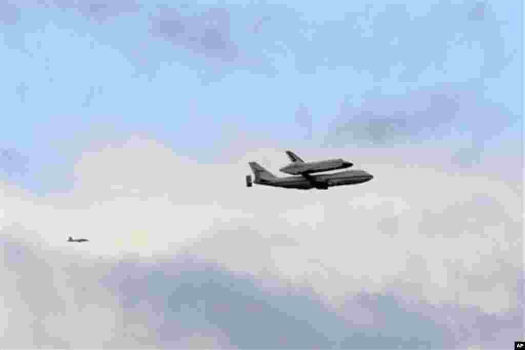 A fighter jet follows as the Space shuttle Enterprise, riding on the back of the NASA 747 Shuttle Carrier Aircraft, flies past Jersey City, N.J., Friday, April 27, 2012. Enterprise is eventually going to make its new home in New York City at the Intrepi