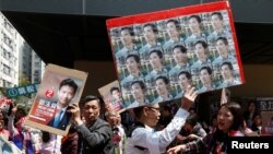 A supporter carrying photos of pro-democracy candidate Edward Yu walks past a supporter of Vincent Cheng from Democratic Alliance for the Betterment and Progress of Hong Kong, during a Legislative Council by-election in Hong Kong, March 11, 2018.