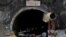 Members of rescue teams stand at the entrance of a tunnel where road workers are trapped after a portion of the tunnel collapsed in Uttarkashi