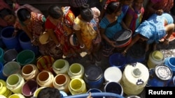 Residents get their containers filled with drinking water from a municipal water tanker at a slum in Kolkata.