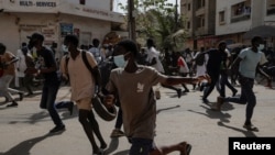 FILE — Senegalese demonstrators run in different directions away during clashes with riot police as they protest the postponement of the February 25 presidential election, in Dakar, Senegal, on February 9, 2024.