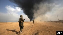 Iraqi forces and members of the Hashed al-Shaabi (Popular Mobilization units) advance toward the city of al-Qaim, in Iraq's western Anbar province near the Syrian border as they fight against remnant pockets of Islamic State group jihadists, Nov. 3, 2017