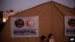 FILE - Rohingya refugee children from Myanmar are seen in front of a Malaysian field hospital near Cox's Bazar, Bangladesh, Jan. 27, 2018. The IFRC has opened two such facilities in Cox's Bazar to help fight the spread of COVID-19.