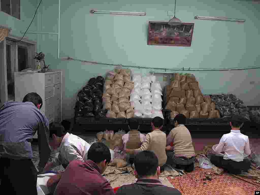 Syrian boys help to fill bags of food aid in a house in a neighborhood in Damascus. (AP)