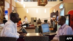 FILE - Men work on their laptops at an internet cafe in Kampala, Nov. 11, 2011.