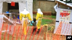 Photo taken Sept 9, 2018, shows health workers walking with a boy suspected of having the Ebola virus at an Ebola treatment centre in Beni, Eastern Congo.