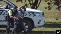 FILE - A demonstrator is frisked by a military police officer after a protest against the policies of President Jair Bolsonaro's government, at the Ministries Esplanade, in Brasilia, Brazil, June 21, 2020. 