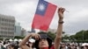 A person poses with Taiwan's national flag for a photo during National Day celebrations in front of the Presidential Building in Taipei, Taiwan, Oct. 10, 2024. 