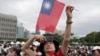 A person poses with Taiwan's national flag for a photo during National Day celebrations in front of the Presidential Building in Taipei, Taiwan, Oct. 10, 2024. 