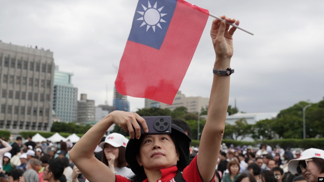 A person poses with Taiwan's national flag for a photo during National Day celebrations in front of the Presidential Building in Taipei, Taiwan, Oct. 10, 2024. 