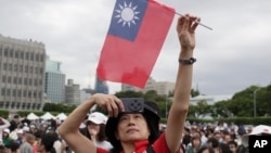 A person poses with Taiwan's national flag for a photo during National Day celebrations in front of the Presidential Building in Taipei, Taiwan, Oct. 10, 2024. 