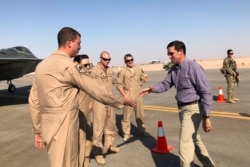 FILE - Defense Secretary Mark Esper talks with U.S. troops in front of an F-22 fighter jet deployed to Prince Sultan Air Base in Saudi Arabia, Oct. 22, 2019.