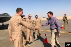 Defense Secretary Mark Esper talks with U.S. troops in front of an F-22 fighter jet deployed to Prince Sultan Air Base in Saudi Arabia, Tuesday, Oct. 22, 2019. (AP Photo/Lolita Baldor)