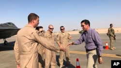 Defense Secretary Mark Esper talks with U.S. troops in front of an F-22 fighter jet deployed to Prince Sultan Air Base in Saudi Arabia, Tuesday, Oct. 22, 2019.