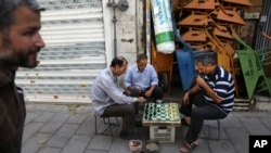FILE - Men play chess outside their shop in downtown Tehran, Iran, July 17, 2019.
